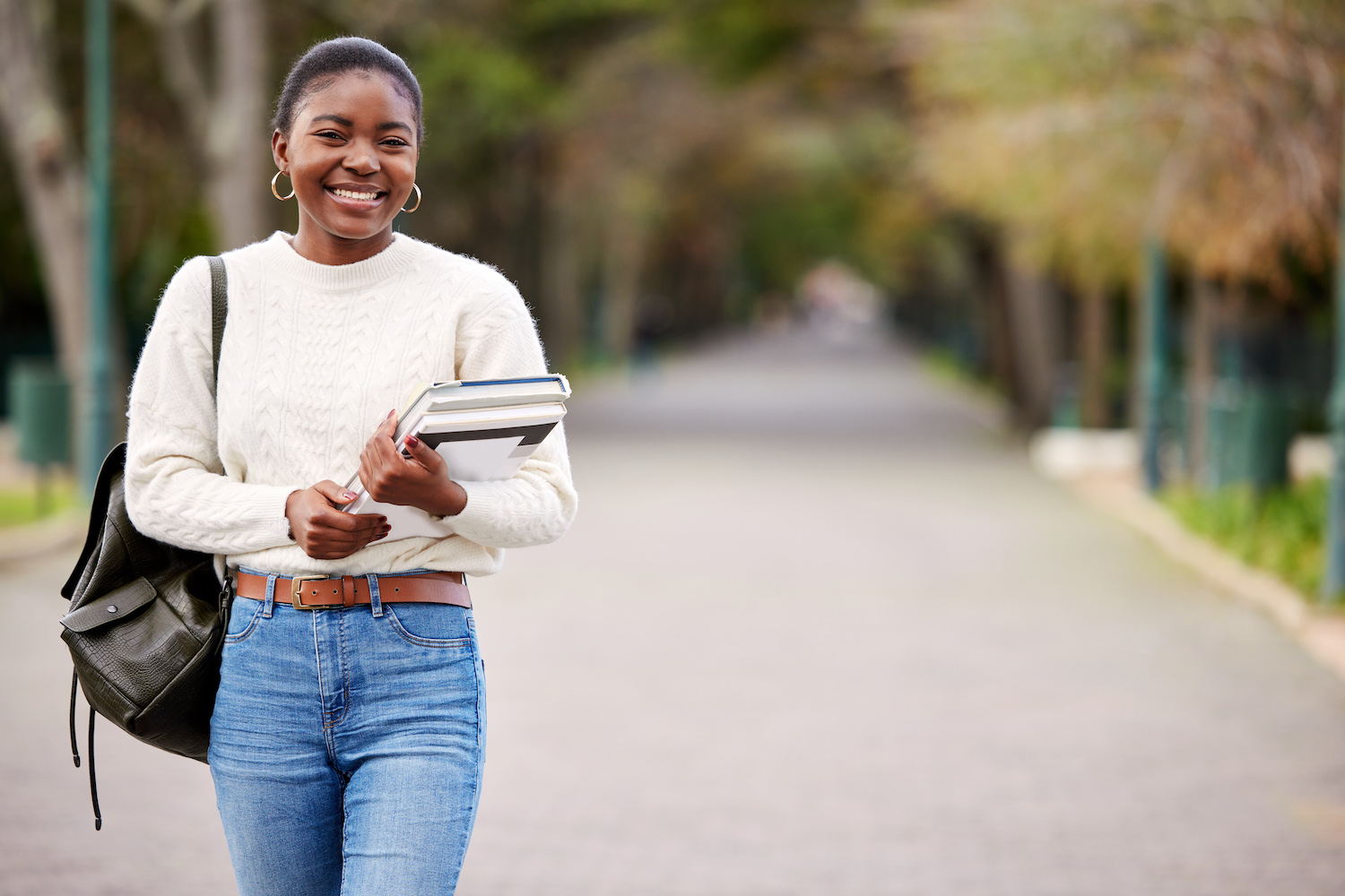 Shot of a young woman carrying her schoolbooks outside at college